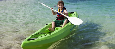 Una persona en kayak verde sobre aguas transparentes.