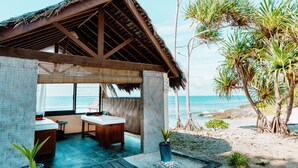 A beachside cabana with a thatched roof, a wooden table, and a bench. - Nasama Resort (Port Vila)