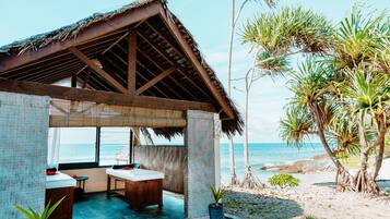 Relax in a beachfront haven with a thatched-roof shelter, seating area, and ocean views.