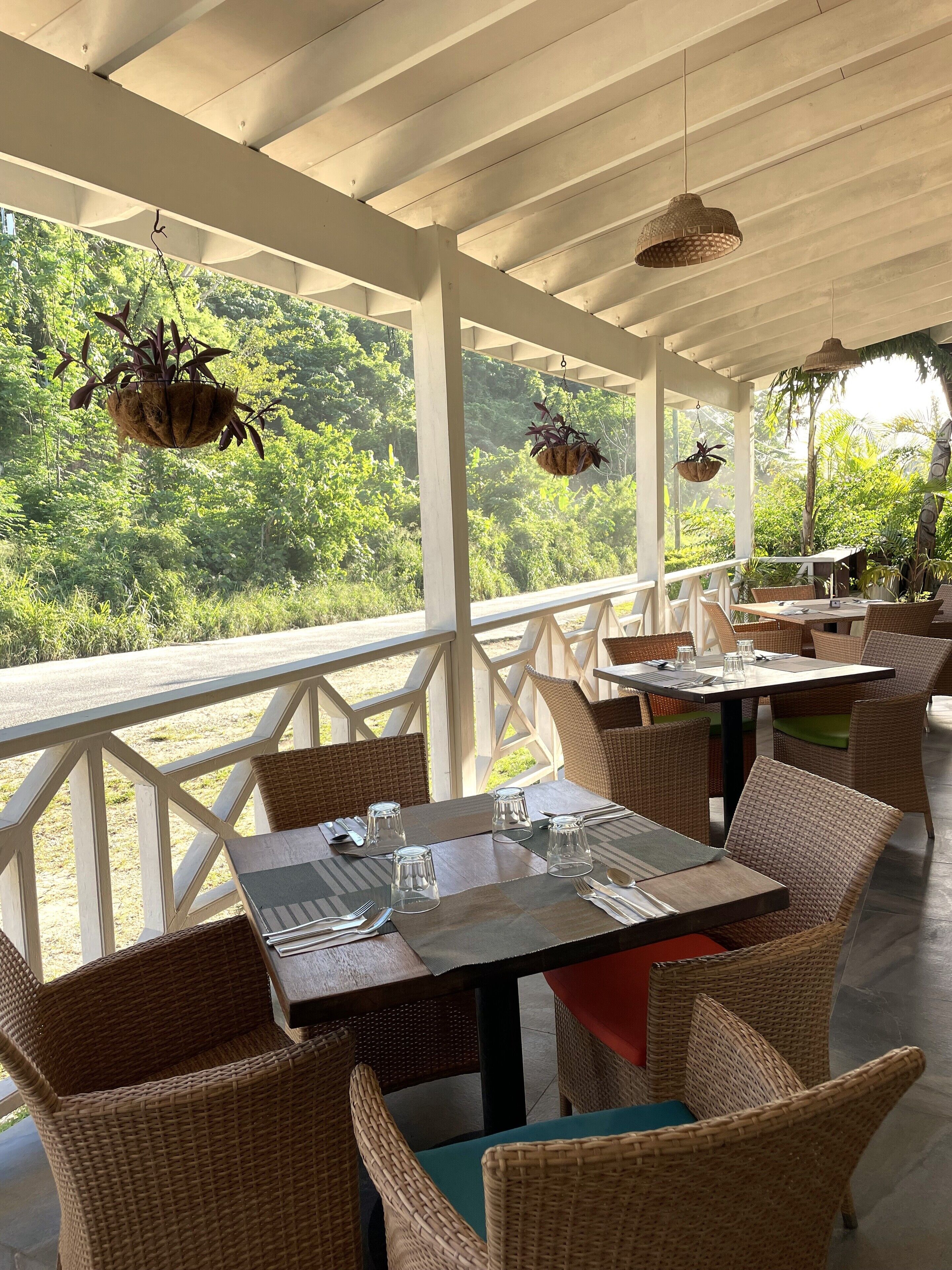 A covered outdoor dining area with wicker furniture and hanging planters.