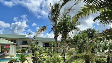 A resort with a pool, palm trees, and a clear sky.