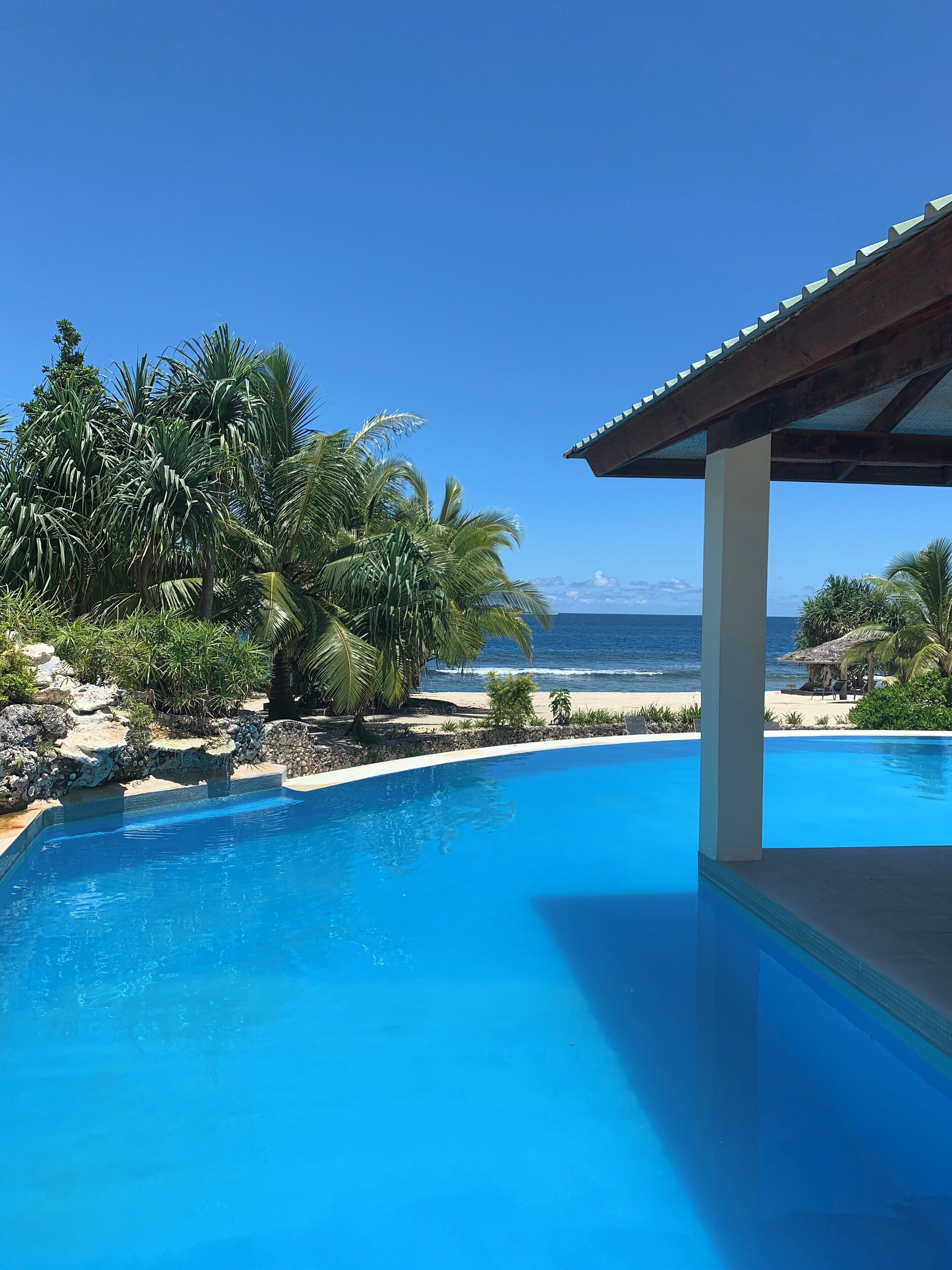 A clear blue pool with a view of the beach and ocean.