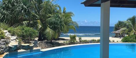 A clear blue pool with a view of the beach and ocean.