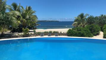 Una piscina al aire libre, sombrillas, sillones reclinables de piscina