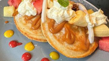 A plate with pancakes topped with whipped cream, caramel, and fruit.