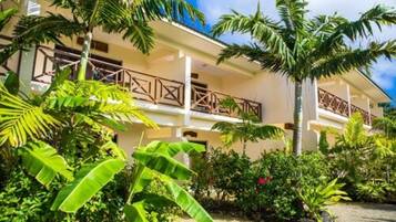 A hotel with a two-story structure, balconies with wooden railings, and lush tropical vegetation.