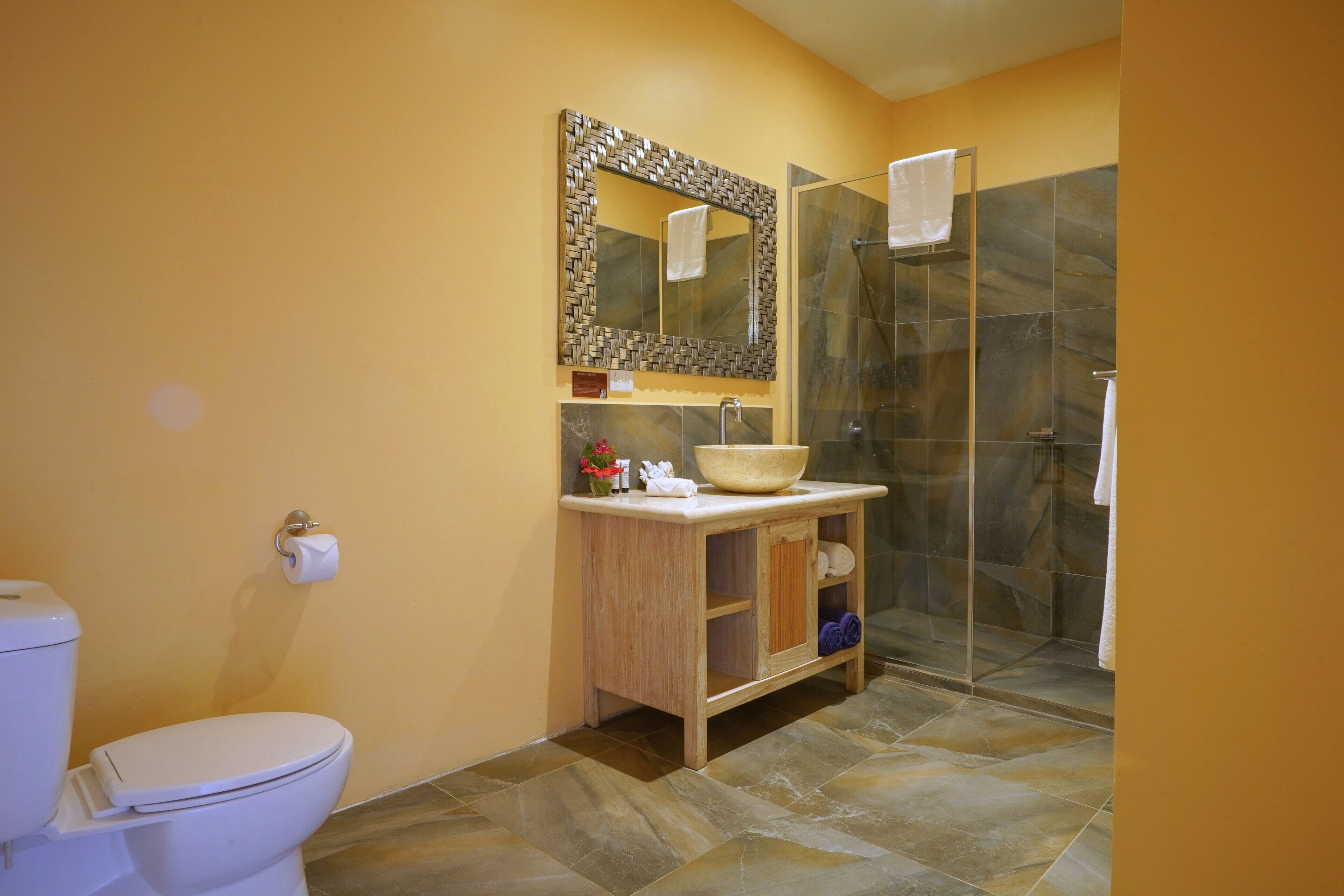 A bathroom with a toilet, sink, mirror, and shower.