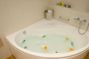 A large bathtub with a champagne bottle, glasses, and flowers in the water. - Diadem (Omis)