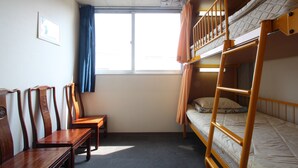 Habitación con literas, una ventana, un escritorio y dos sillas.