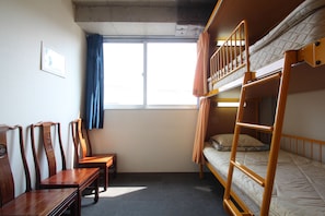 Habitación con literas, una ventana, un escritorio y dos sillas.
