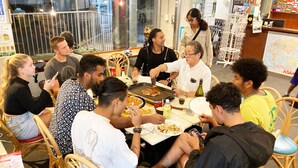 Un grupo de personas cenando en un restaurante con vistas amplias a través de un gran ventanal.