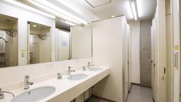 A public restroom with three sinks, a large mirror, and a paper dispenser.