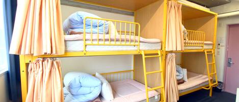 A bunk bed room with curtains, a ladder, and a door.