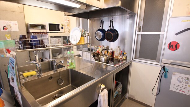 Una cocina con electrodomésticos de acero inoxidable, un lavamanos y diversos utensilios de cocina.