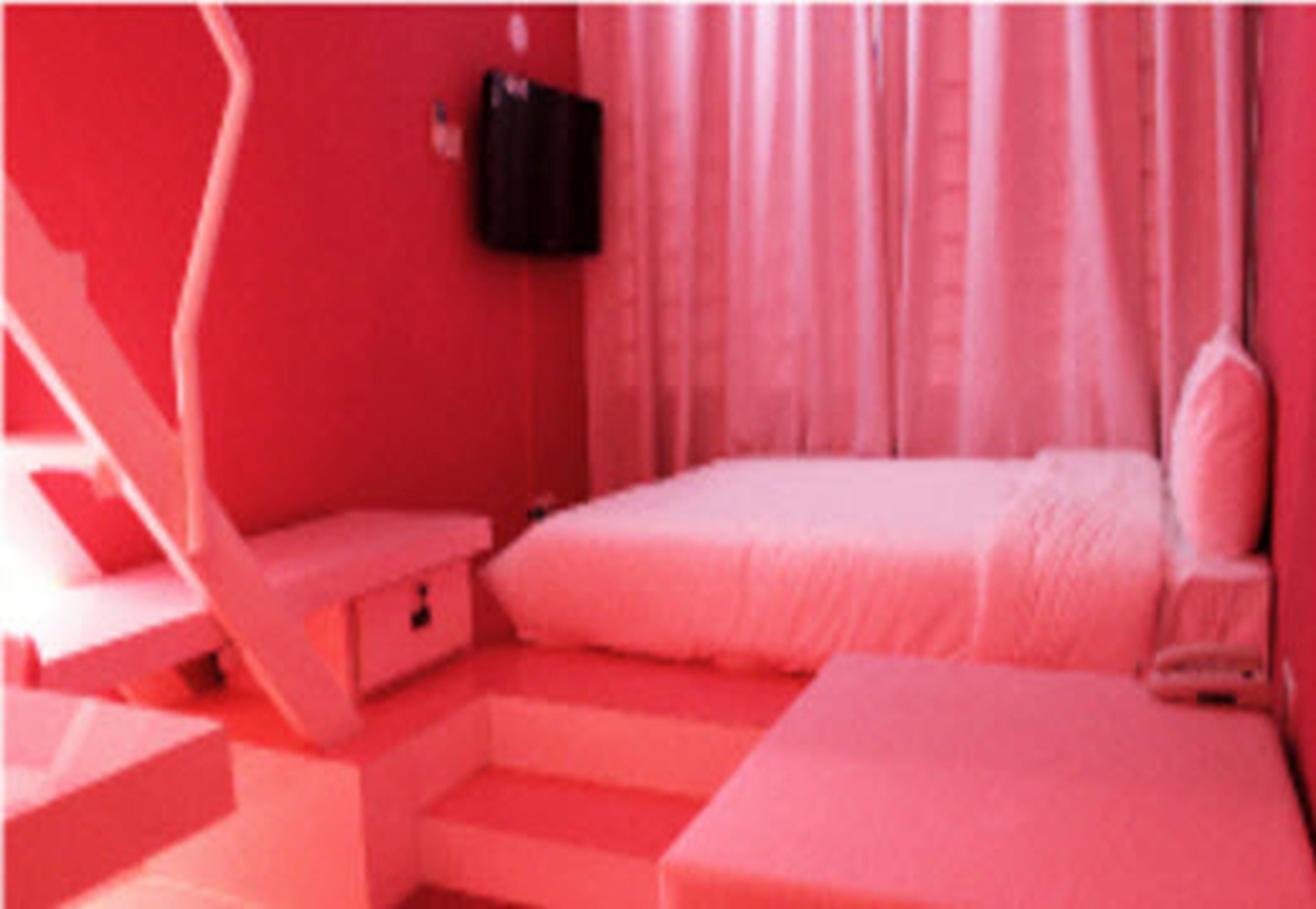 A pink-themed bedroom with a bed, a nightstand, and a chair.