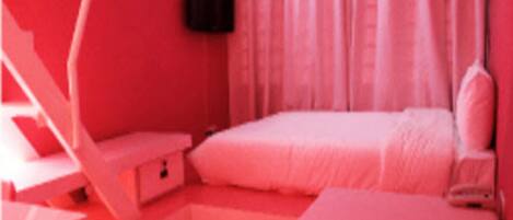 A pink-themed bedroom with a bed, a nightstand, and a chair.