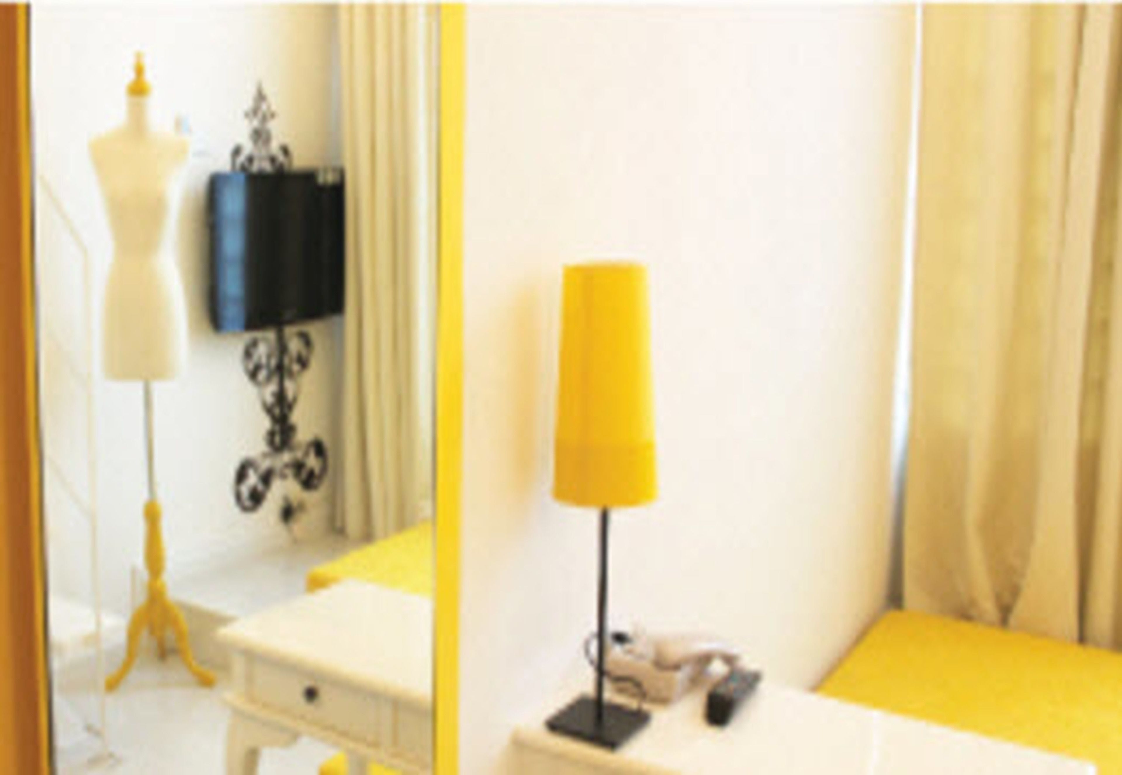 A room with a white dresser, a yellow lamp, and a mannequin in the corner.