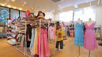 Tienda de ropa con perchas llenas de vestidos y un maniquí.