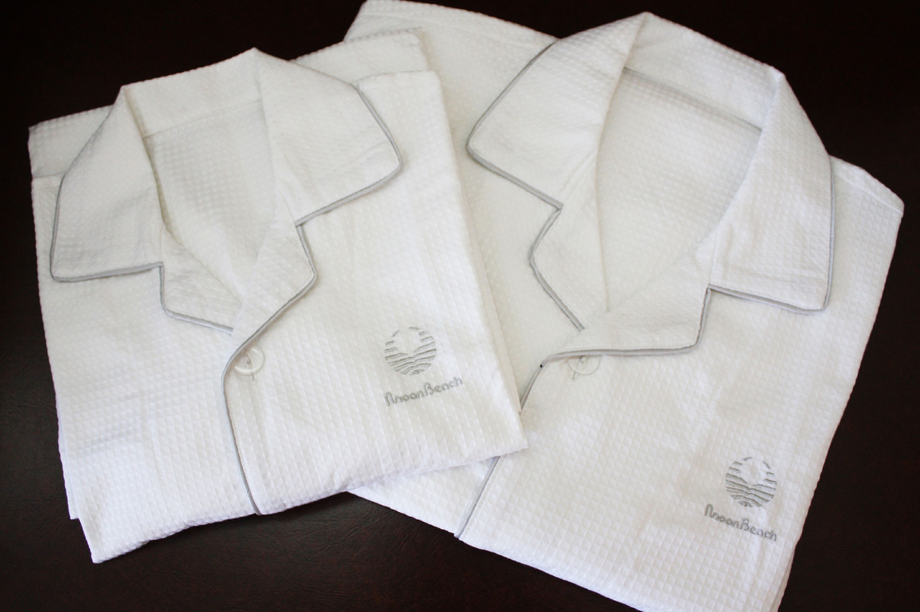 Two neatly folded white shirts with a logo on the left chest area.