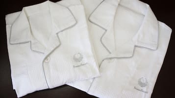 Two neatly folded white shirts with a logo on the left chest area.