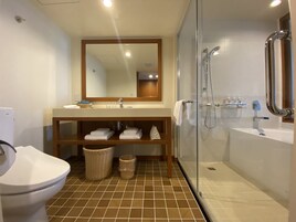 A bathroom with a glass-enclosed shower, a sink, a toilet, and a mirror above the sink.