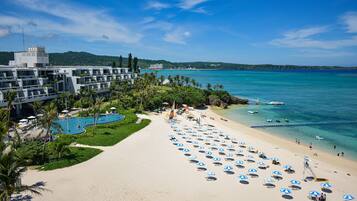 Relax by the beachfront pool surrounded by lush greenery and palm trees.