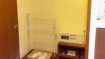 Une chambre d’hôtel avec une serviette blanche et des chaussons sur un tapis, un radiateur blanc et un panneau de commande avec des instructions.