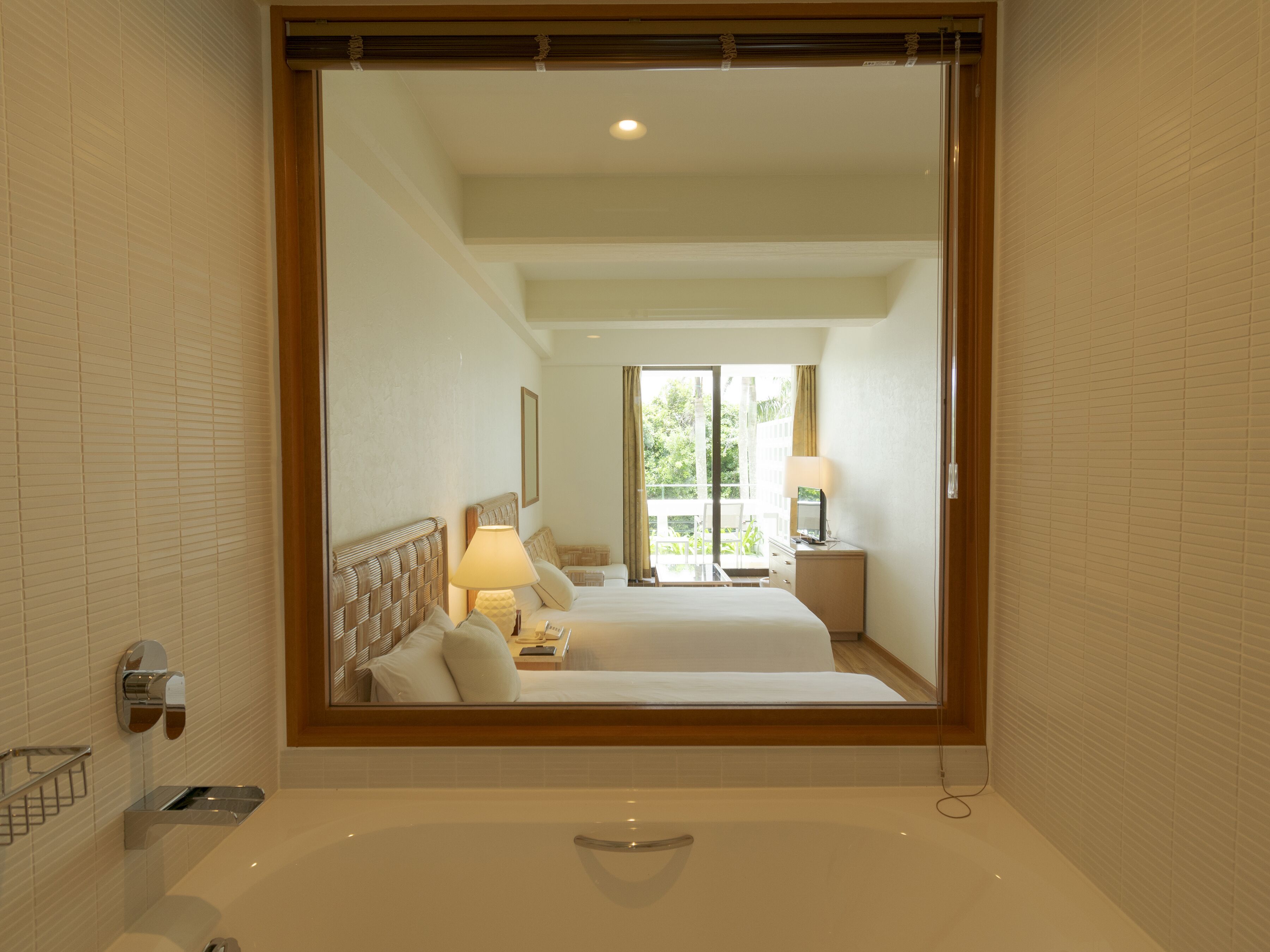 A hotel bathroom with a large mirror, a bathtub, and a shower area.