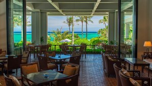 A restaurant with outdoor seating overlooking a beach and ocean. - THE MOON BEACH MUSEUM RESORT (Onna)
