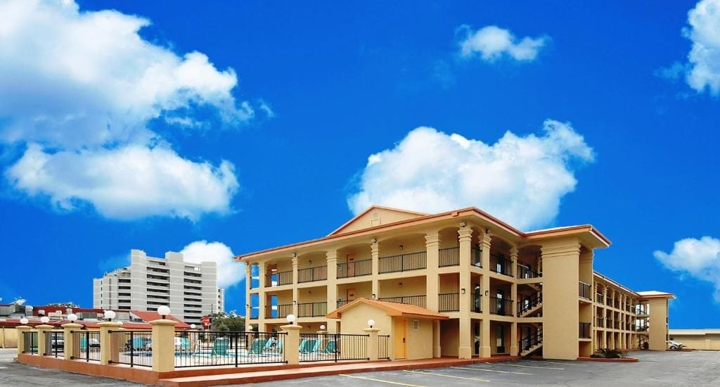 Un hotel de varios pisos con un patio central, balcones y una zona de piscina.
