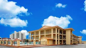 A multi-story hotel with a central courtyard, balconies, and a pool area.