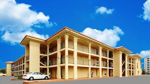 Un hôtel à plusieurs étages, doté d’une façade symétrique, de balcons et d’une voiture garée devant.
