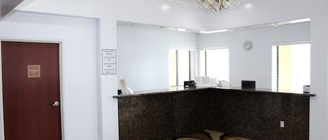 A reception area with a dark granite counter, a clock on the wall, and a door with a sign.