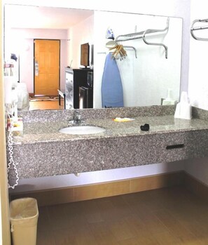 A bathroom with a granite countertop, a sink, a mirror, and a towel rack.