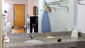 Une salle de bain avec un comptoir en granit, un lavabo, un miroir et un porte-serviettes.