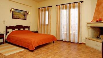 Un dormitorio con cama, cortinas, chimenea y un cuadro en la pared.