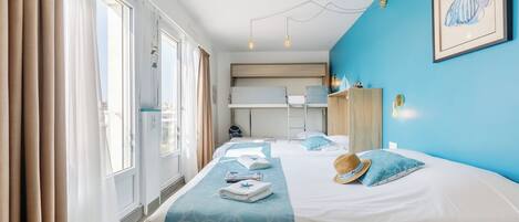 Una habitación de hotel con una cama grande, una litera, un armario y un escritorio.
