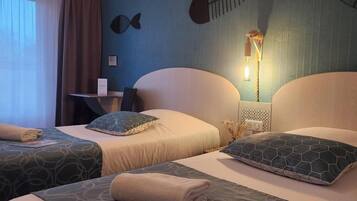 Habitación de hotel con dos camas, un escritorio y una lámpara fijada a la pared.