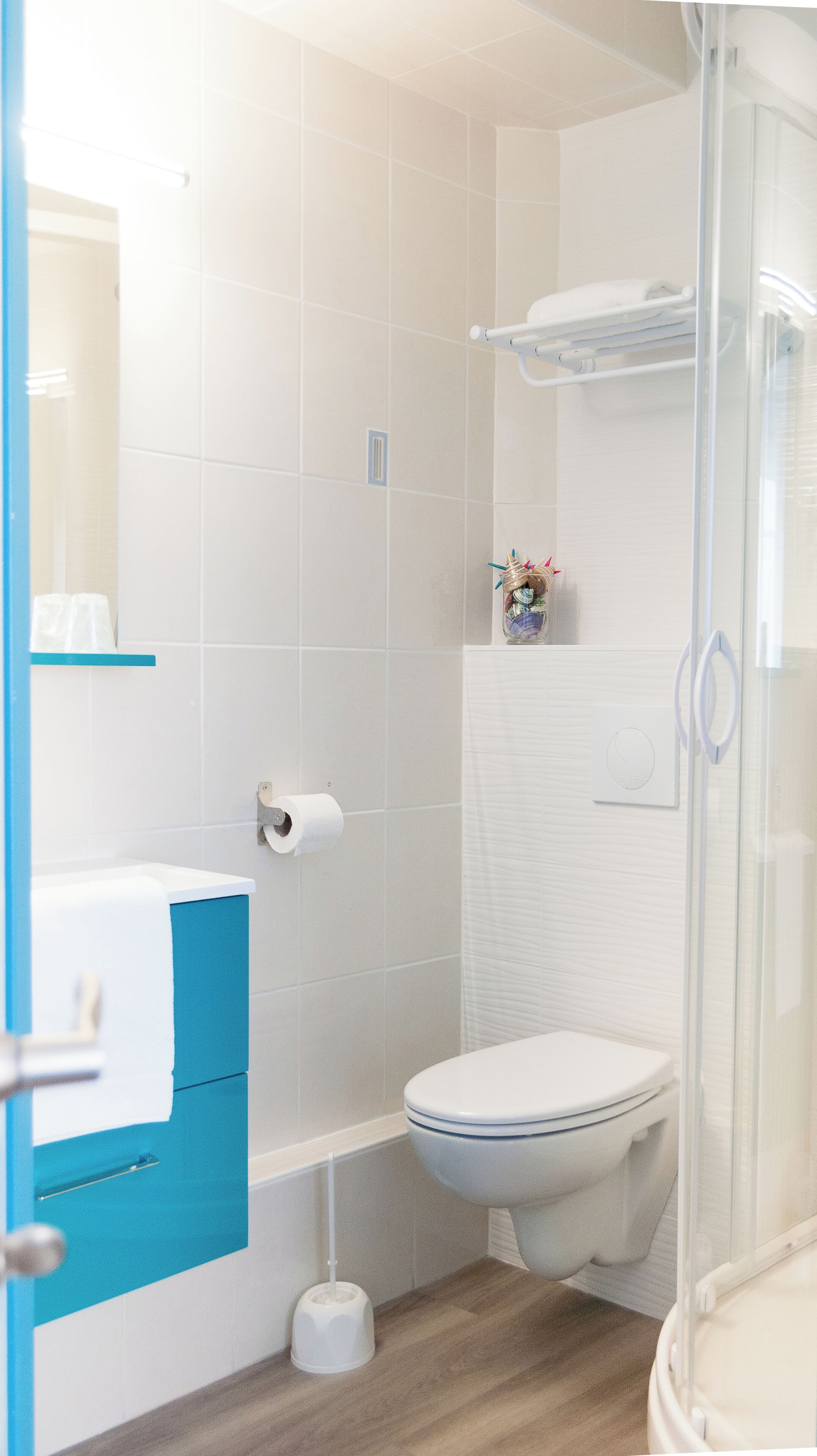 Un baño con inodoro, ducha y zona de ducha con mampara de vidrio.