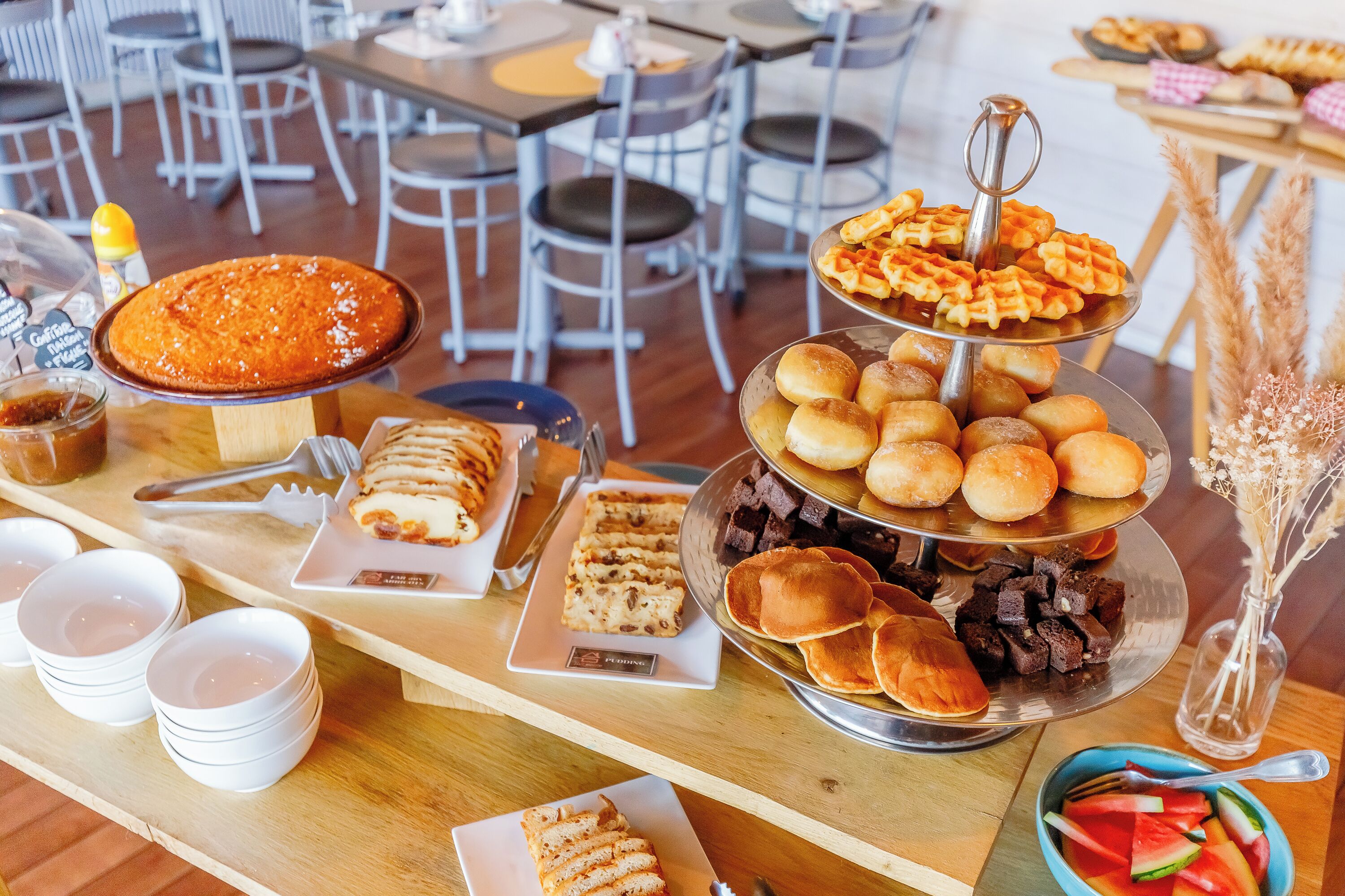 A buffet table with various food items including waffles, bread, and desserts.