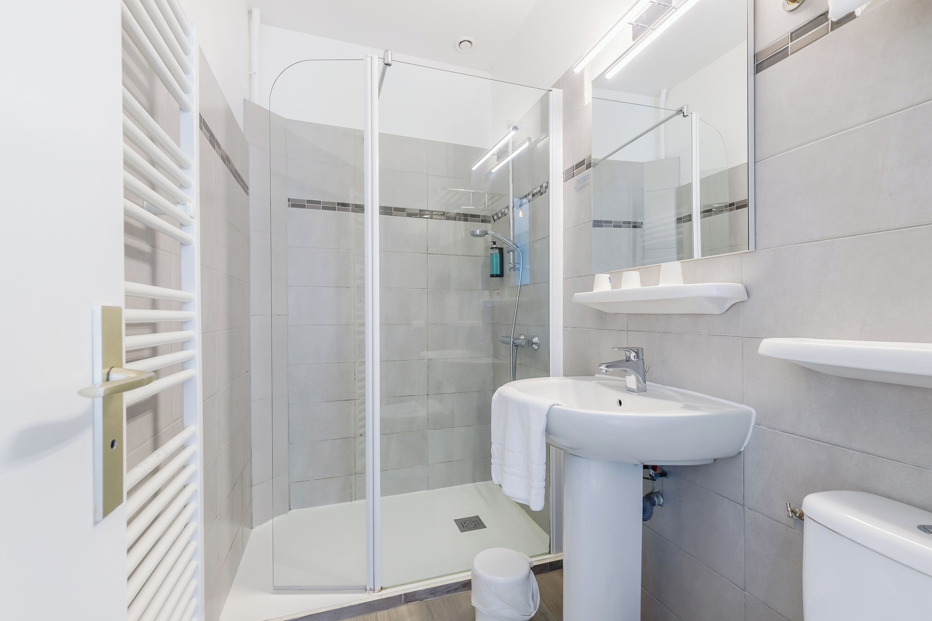 A modern bathroom with a glass-enclosed shower, a white sink, and a toilet.