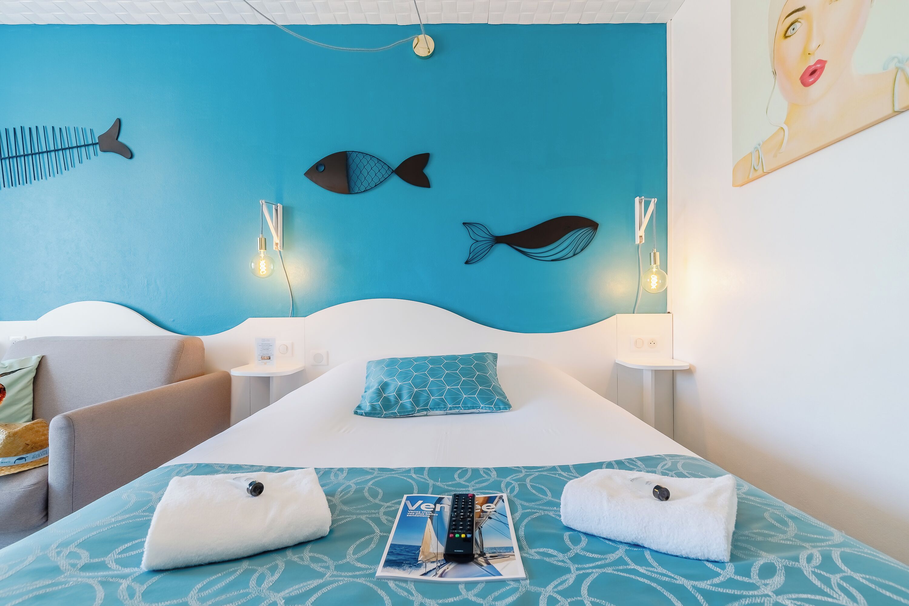 A hotel room with a bed, a chair, a nightstand, and a wall with fish decorations.