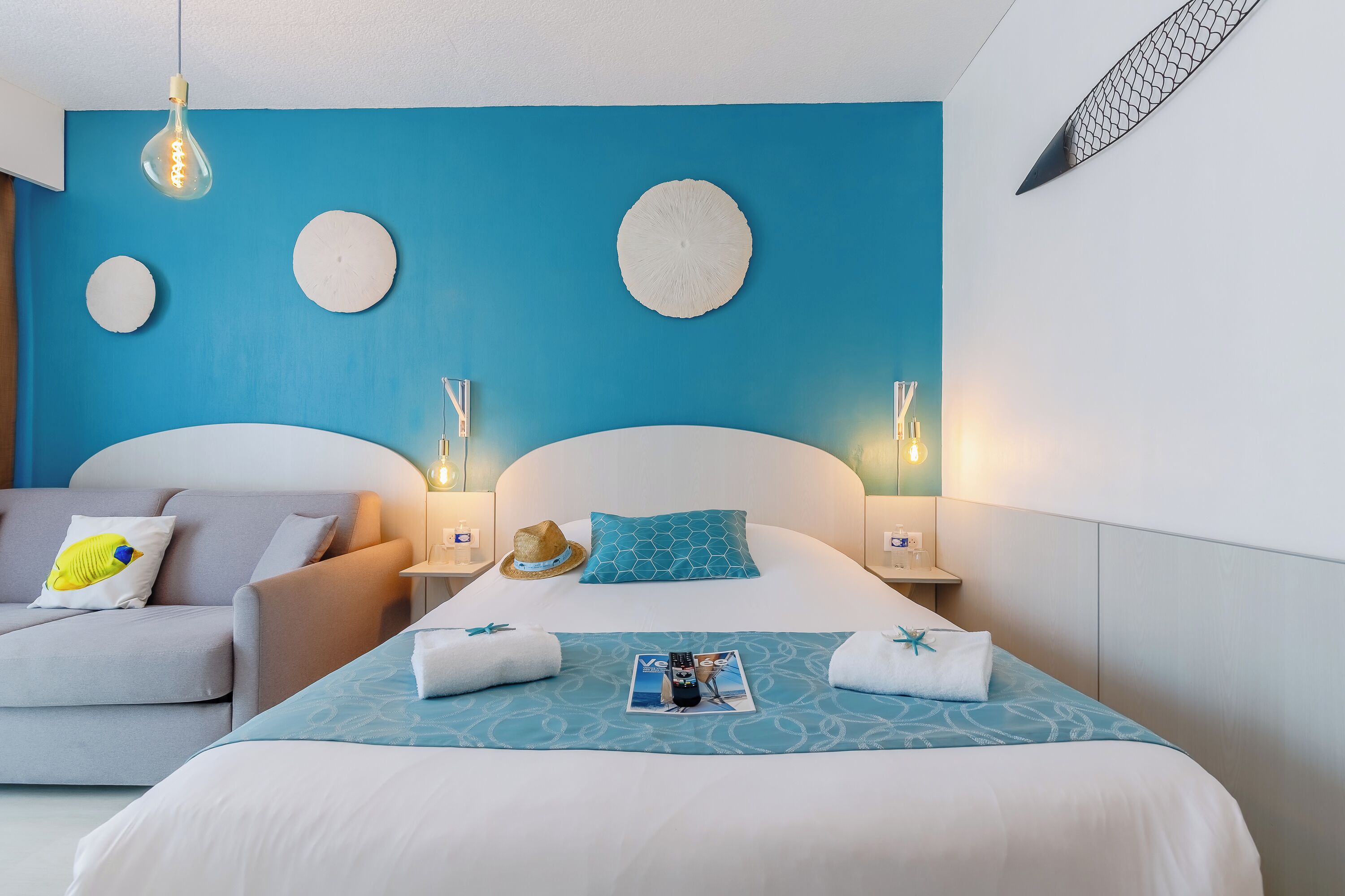 Una habitación de hotel con una cama, un sofá y una mesita de noche con una lámpara.