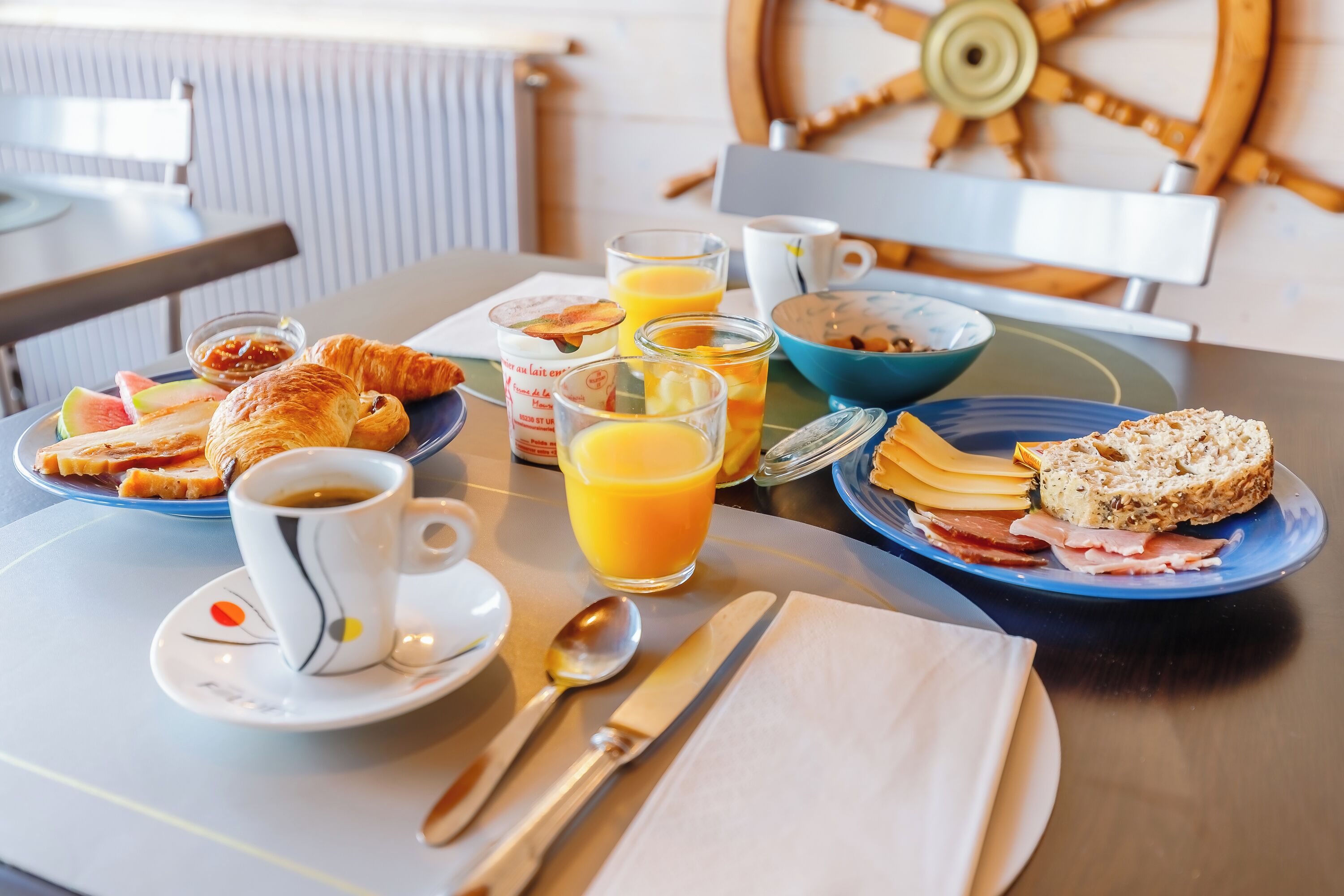 Una mesa de desayuno con cruasanes, queso, jamón y jugo.