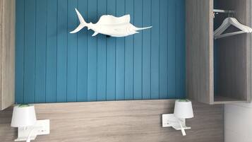 A bedroom with a blue wall, wooden headboard, two bedside tables with lamps, a bed with a white and gray patterned bedspread, and a white wall-mounted shelf with a white fish decoration.