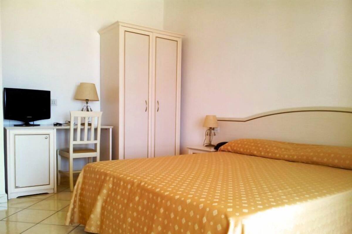 Una habitación de hotel con cama, televisión, escritorio y armario.