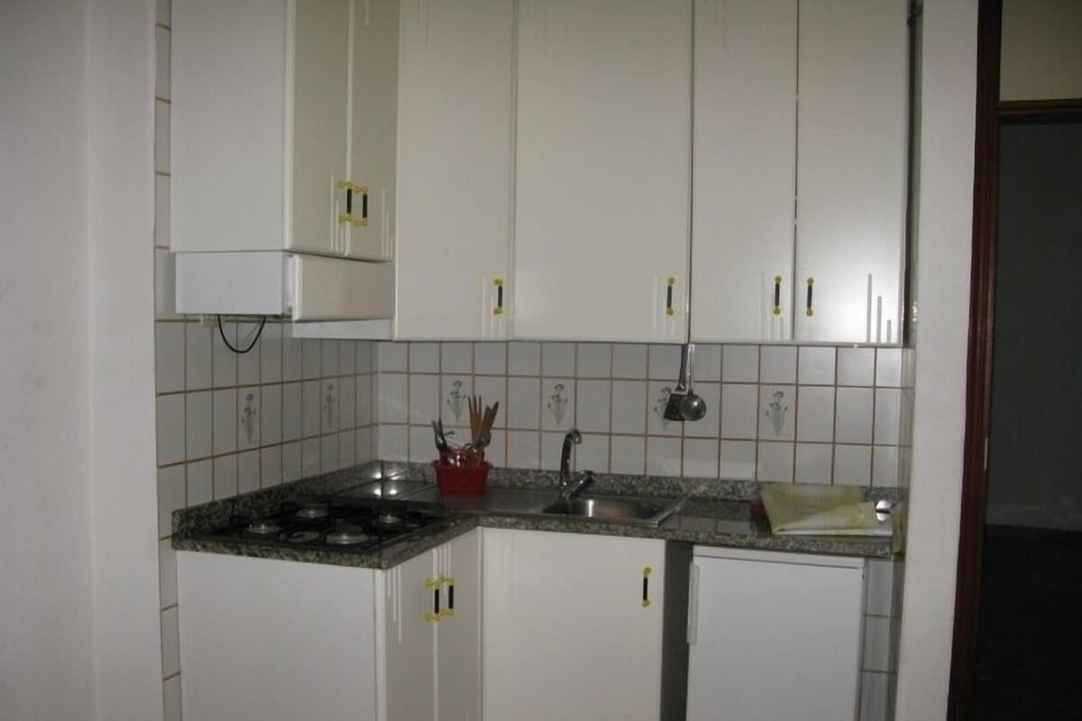 Una cocina con armarios blancos, encimera de granito, estufa a gas y un lavabo.