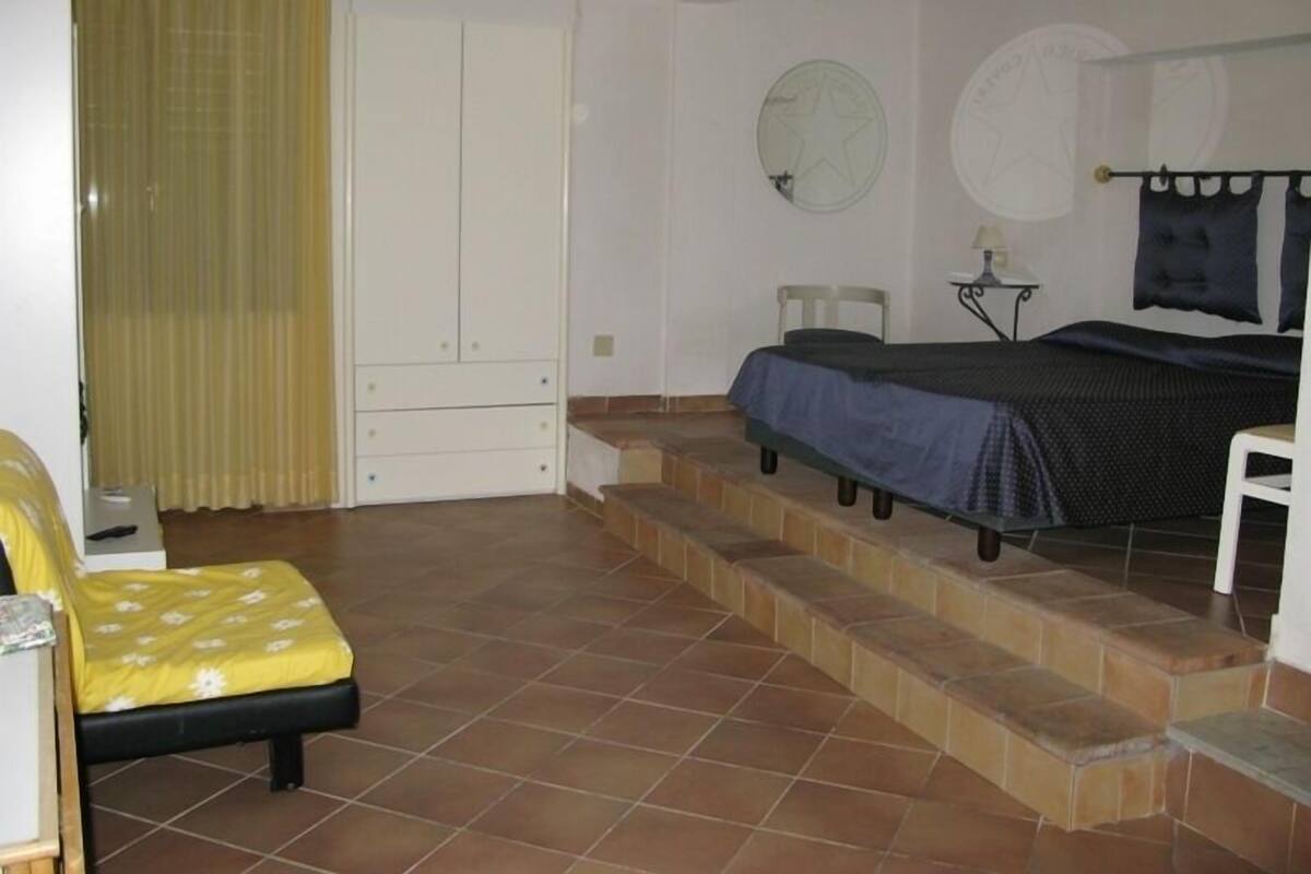 Un dormitorio con cama, una silla, una mesita y un armario.
