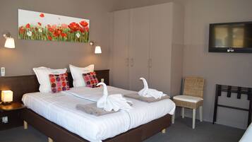 Una habitación de hotel con una cama grande, dos mesitas de noche, un televisor y un cuadro de flores en la pared.
