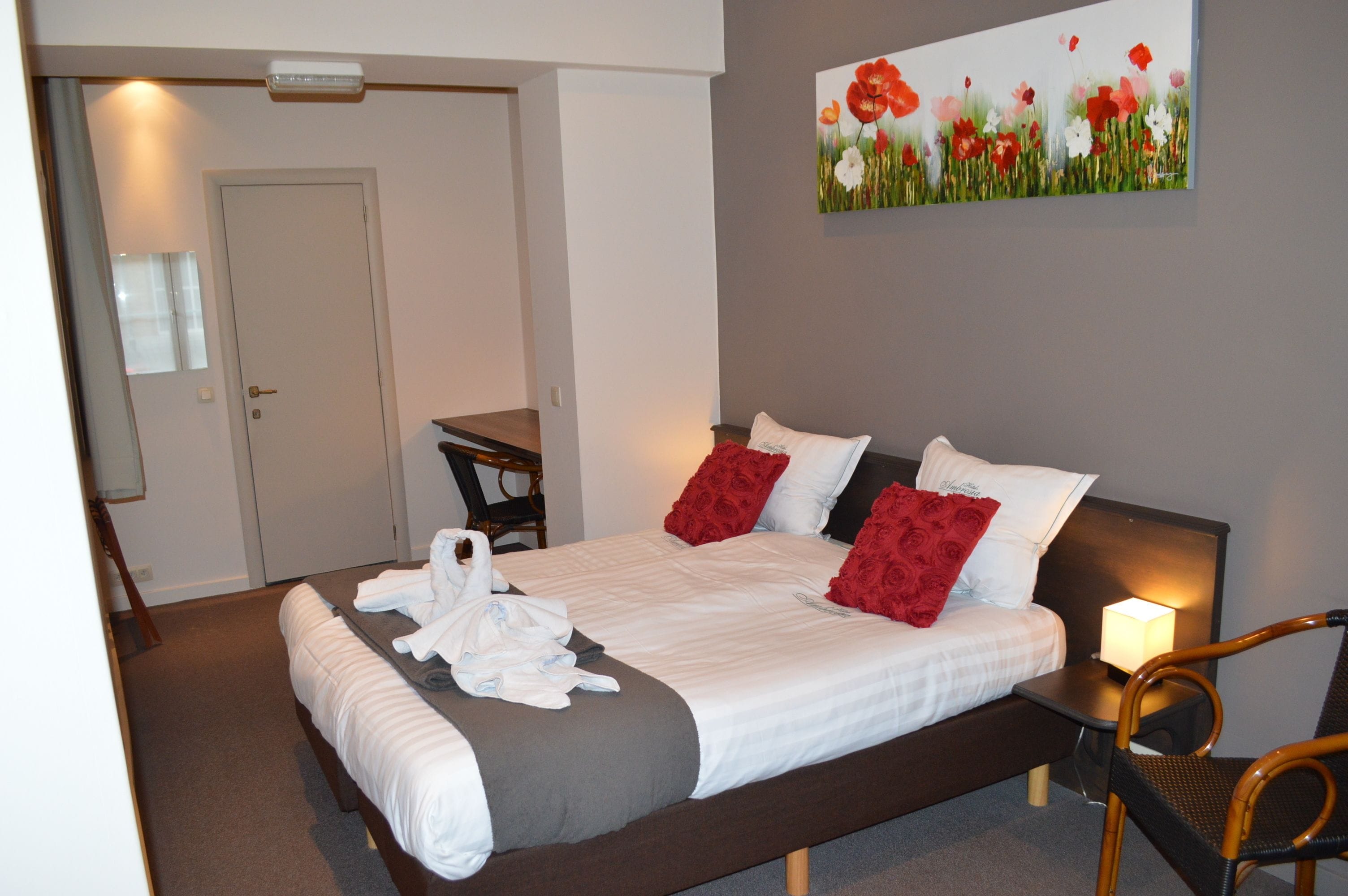 Une chambre d’hôtel avec un lit, une table de chevet, une chaise et un tableau au mur.